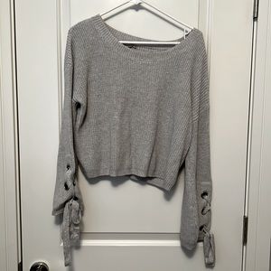 Oversized gray sweater with tie details at the wrist.